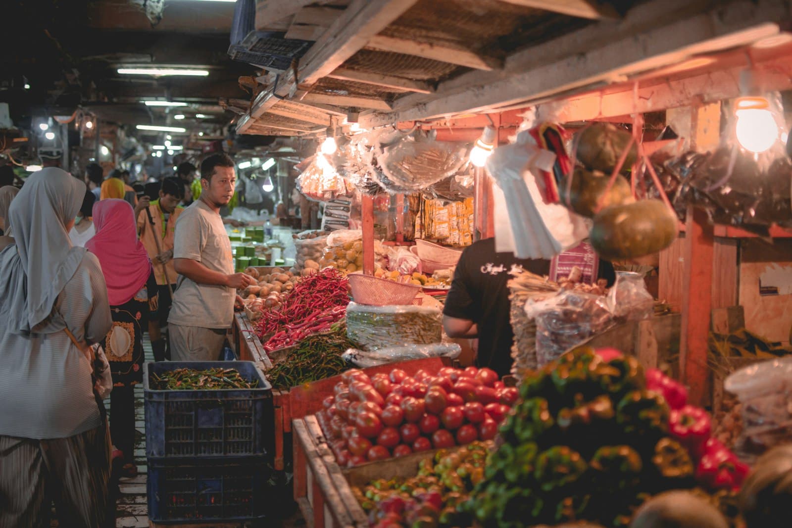 Vendor at a traditional Jakarta market with fresh produce and spices